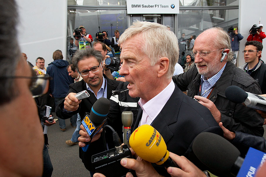 President of FIA Max Mosley is being interviewed whilst he speeds through the paddock
