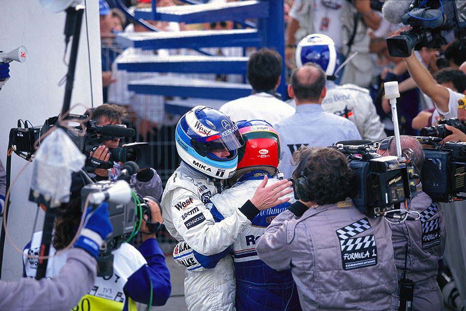 Race winner Mika Hakkinen hugs new 1997 world champion Jacques Villeneuve in parc ferme (who let both McLaren's pass to secure his champioonship)