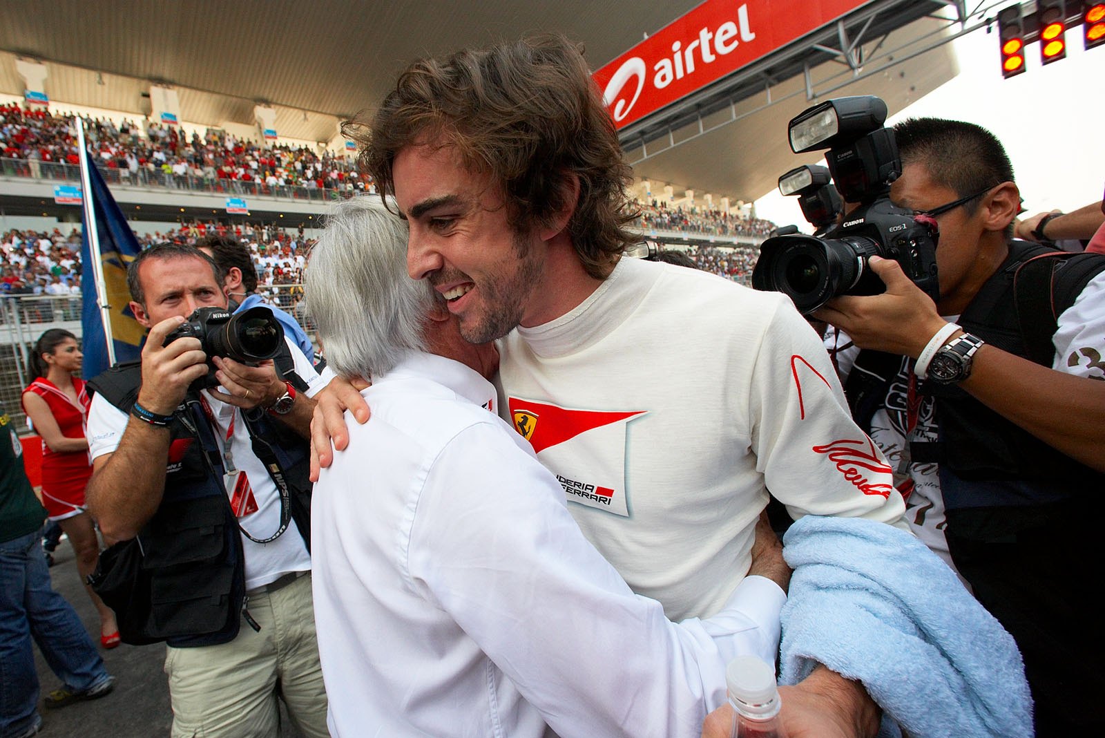 Previously sad but now happy looking Fernando Alonso finds himself in the arms of Bernie Ecclestone