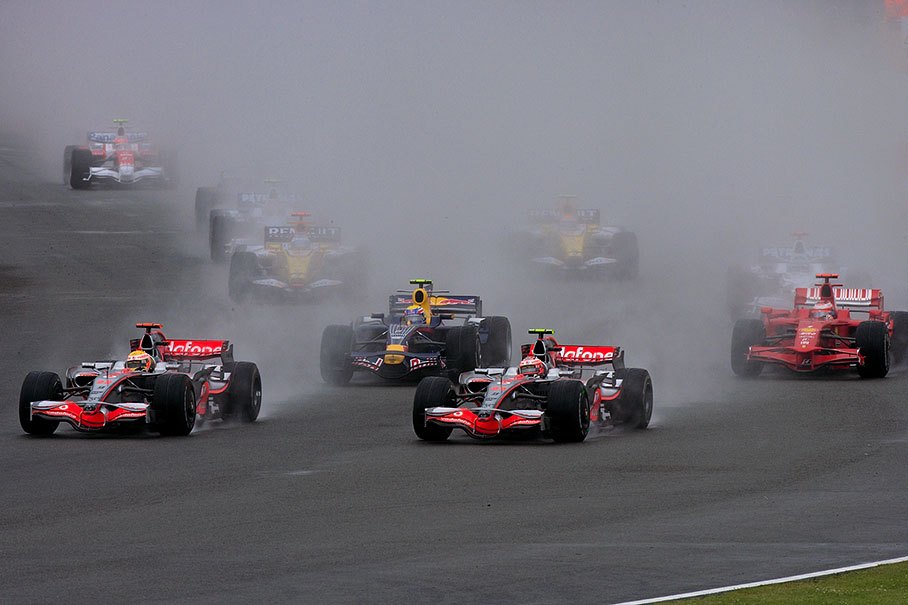 The two McLarens lead the field which disappears in a cloud of spray