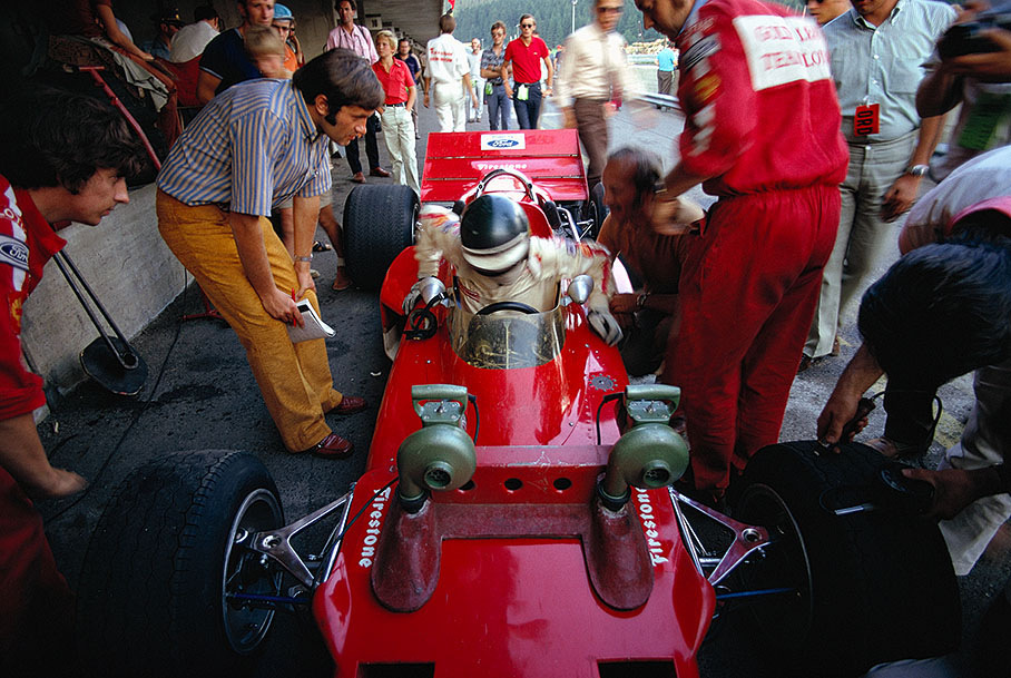 Champioship leader Jochen Rindt getting out of his Lotus 72, watched by Austrian journalist Helmut Zwickl (left), mechanic Herbie Blash (far left) and Colin Chapman (sitting beside the car). Cooling fans are attached above the brake discs.