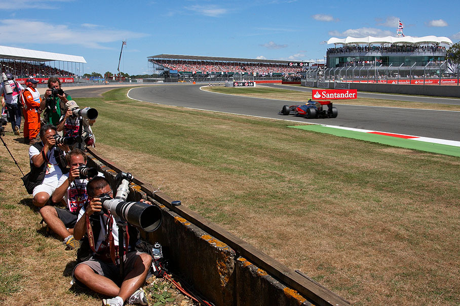 Race photographers sit on the bank besides the race track, Hamilton passes by