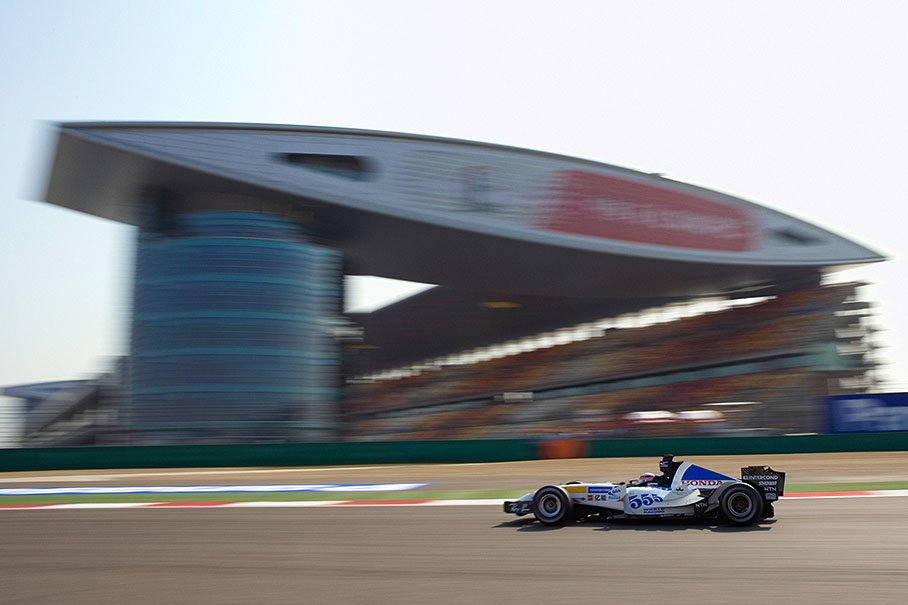 Takuma Sato passing the giant main building.