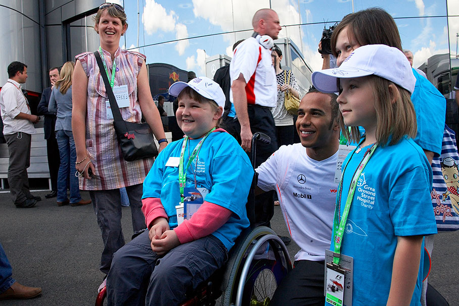Lewis Hamilton poses with young fans for a souvenir photo