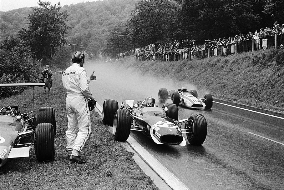 Jo Siffert in his Lotus has just stoped for borrowing a dry visor from retired Graham Hill. John Surtees in his Honda is passing the pair.
