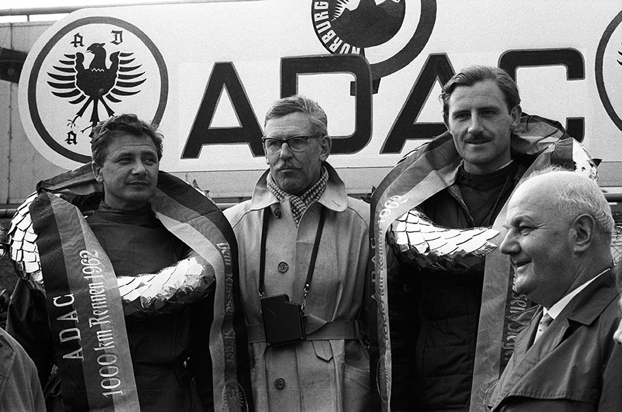 Graham Hill (right hand) and Hans Herrmann (on the left side) become third placed on Porsche and celebrate with Porsche race director Huschke von Hanstein on the podium after the 1000kms Nuerburgring 1962