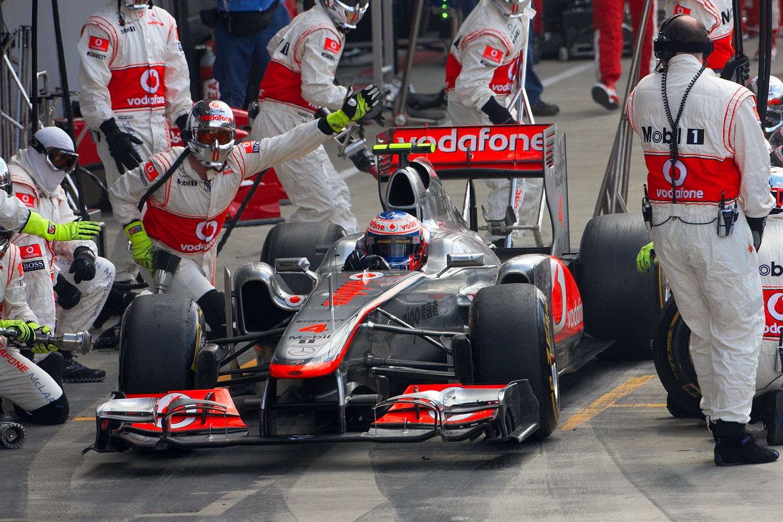 Jenson Button ejects from McLaren pits despite a loose wheel nut right front
