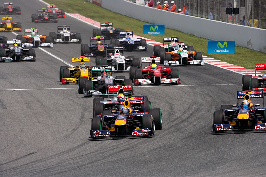 The start field approaches turn one, both Red Bulls in the lead