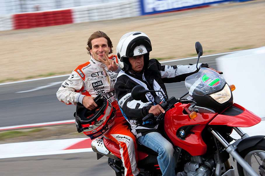 Cheaky Markus Winkelhock returns from practice on a motorcycle with pick-up marshal (questions: is the marshal really a police officer? if so, is markus arrested for not wearing his helmet?;)