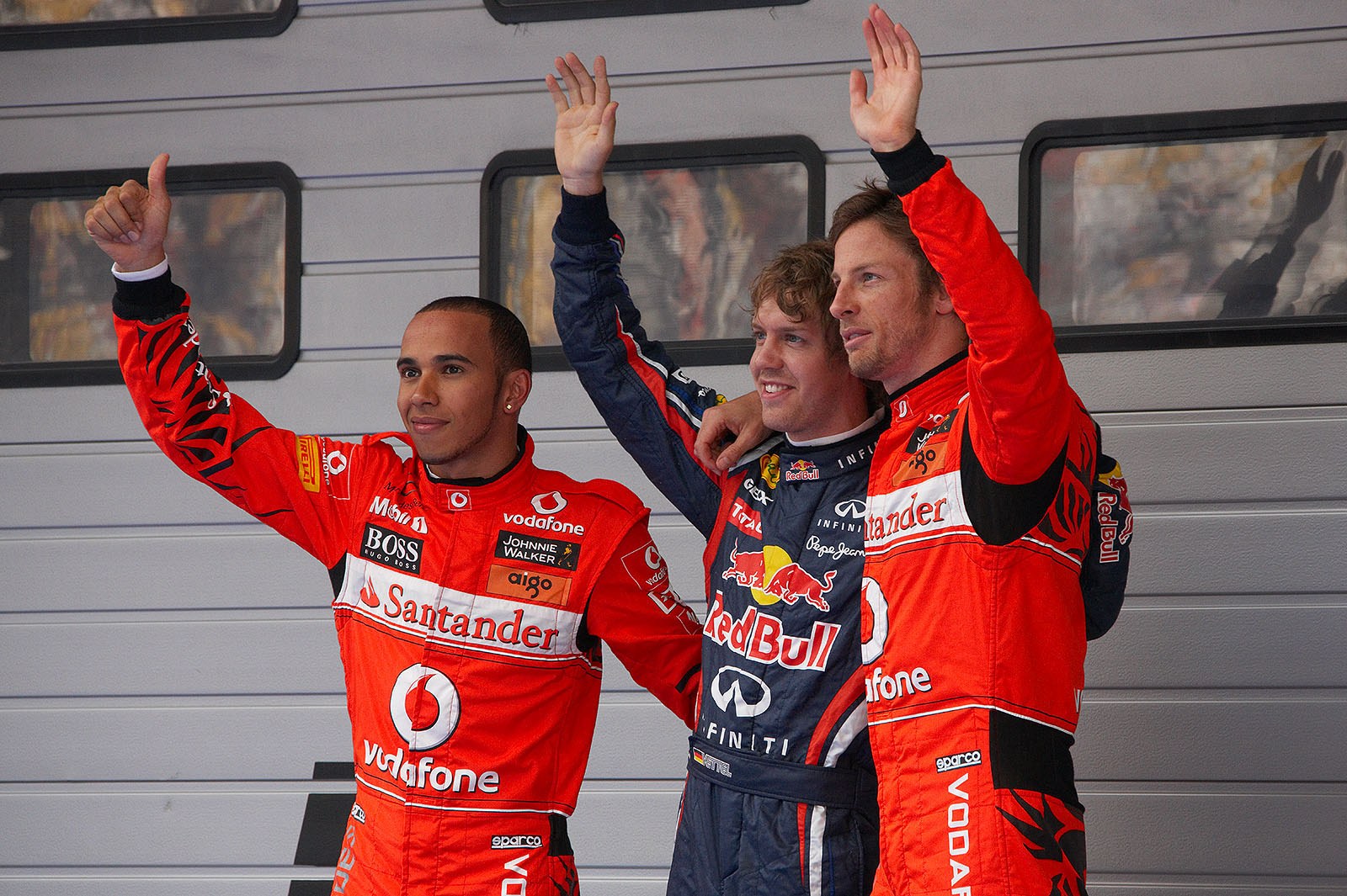 The fastest three qualifiers wave at the world's media: Red Bull driver Sebastian Vettel as polesetter in the middle with third qualified McLaren's Lewis Hamilton and his team mate Jenson Button as second on the grid (note the special driver suits)