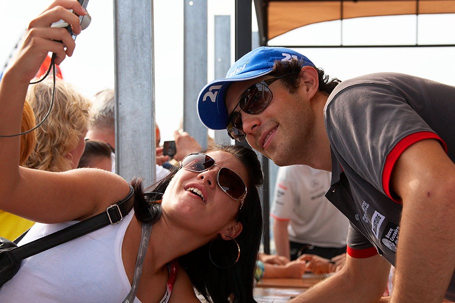 A fan takes a souvenir photo with Bruno Senna