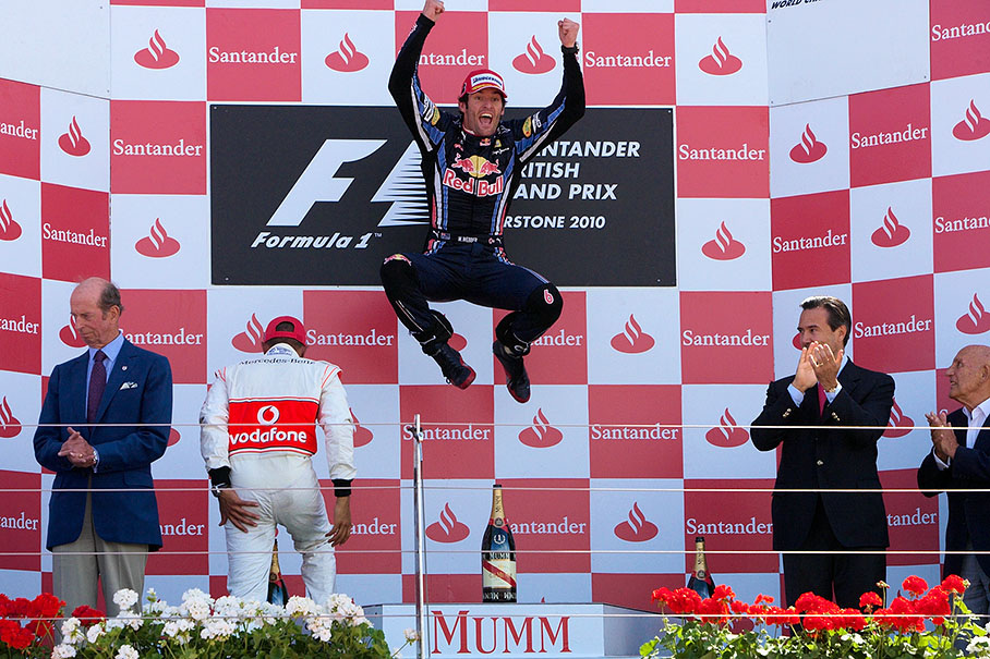 Mark Webber jumps on the podium after winning the British GP 2010