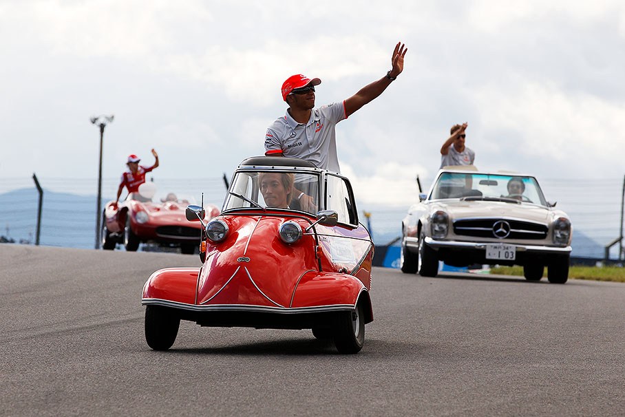 Lewis Hamilton waves at the fans from a historic car during the drivers parade