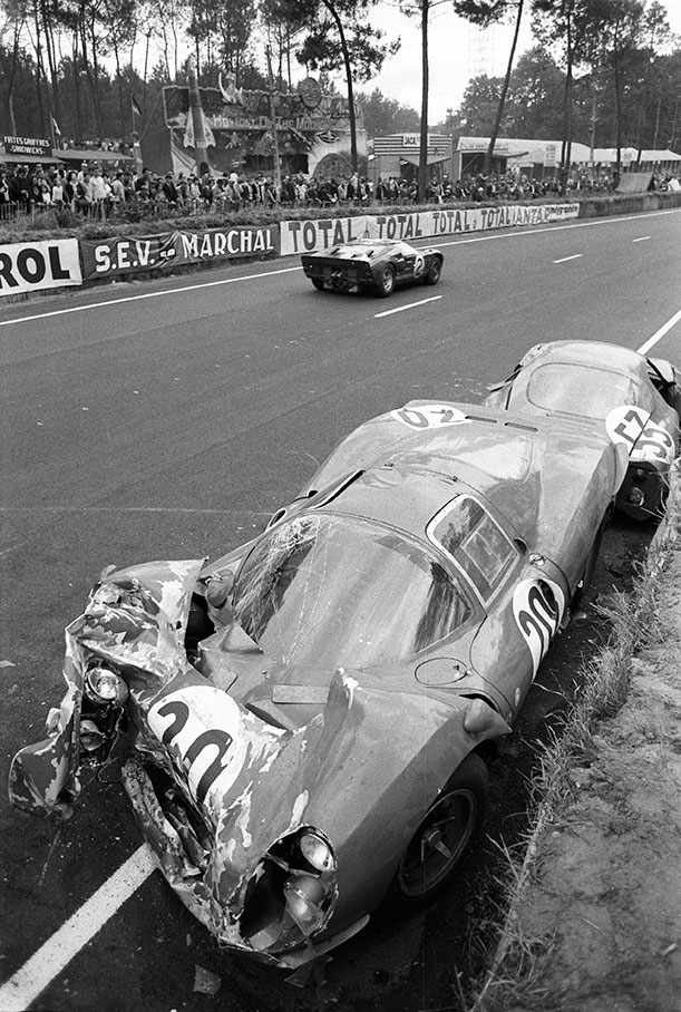 The winning Ford Mk II #1046 of Bruce McLaren (NZ) and Chris Amon (NZ) passes the wrecks of two retired racecars besides the track - car no. 20, the Ferrari 330 P3 #0848 of Mike Parkes (GB) and Ludovico Scarfiotti (I) and car no. 53, the C.D. SP66 Peugeot 663IW75 of Georges Heligouin (F) and Johnny Rives (F).