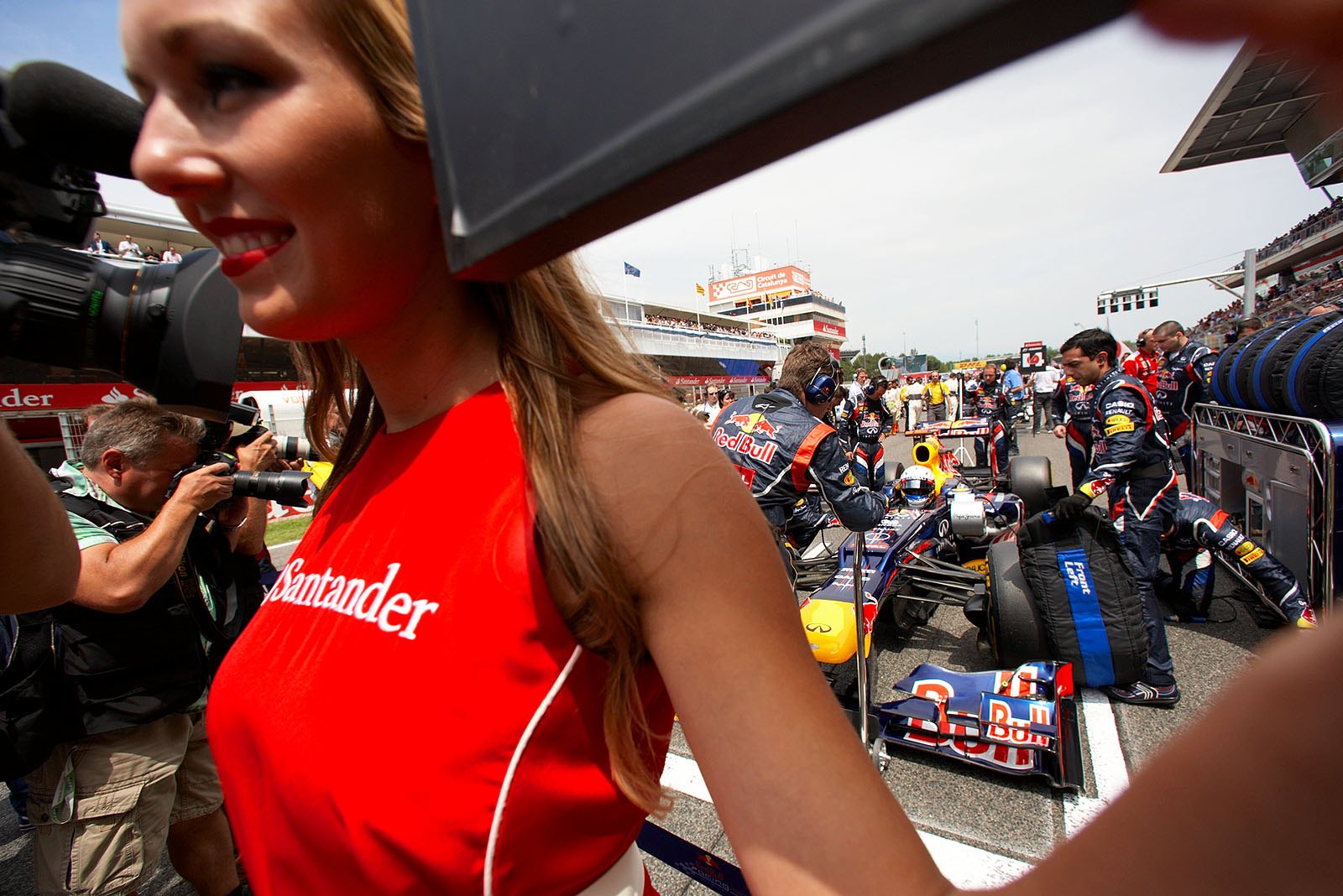 Vettel's grid girl keeps the snappers away from the busy Red Bull mechanics