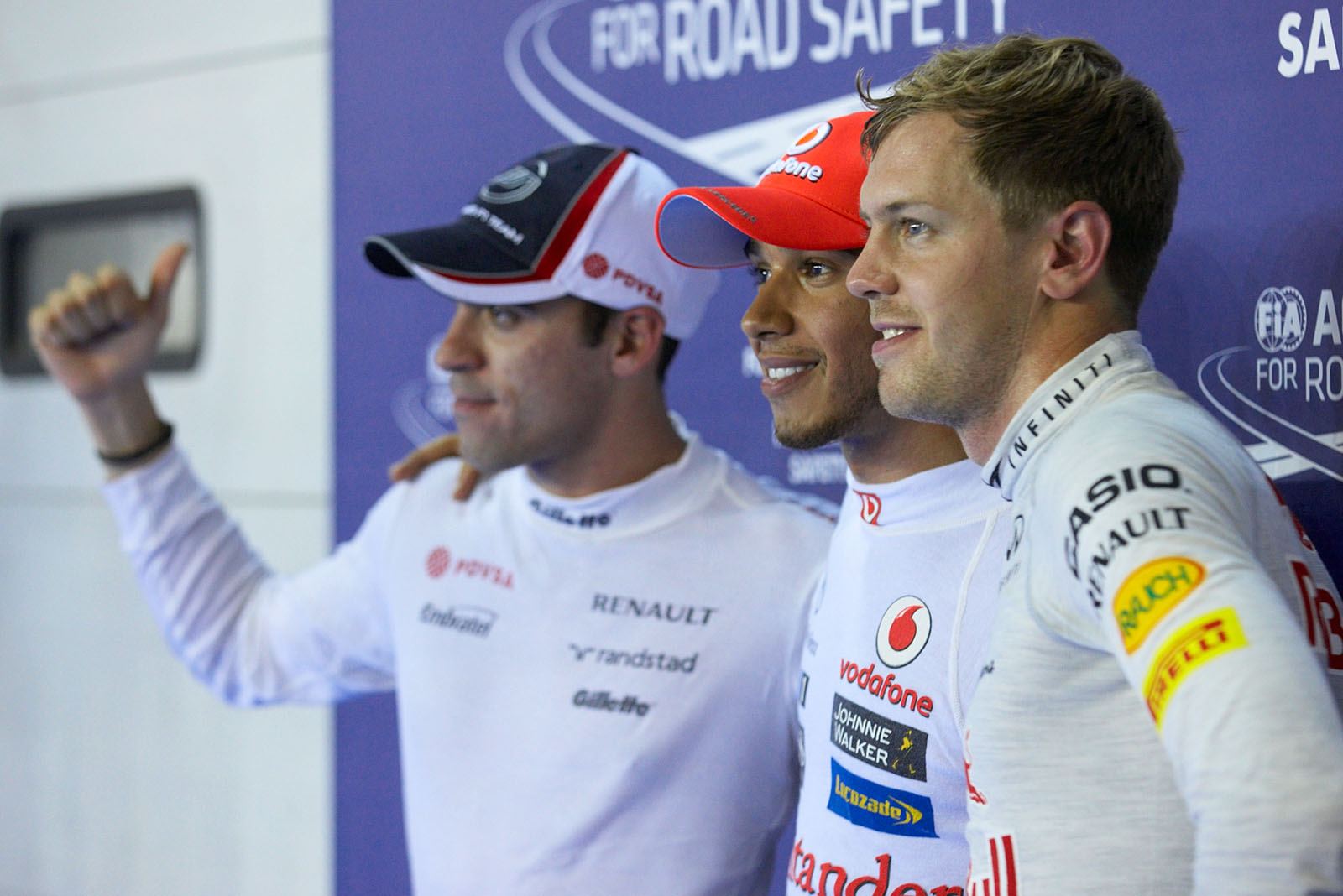 Polesetter Lewis Hamilton of McLaren poses the world's media, flanked by second grid positioned Maldonado and Vettel as third on the grid