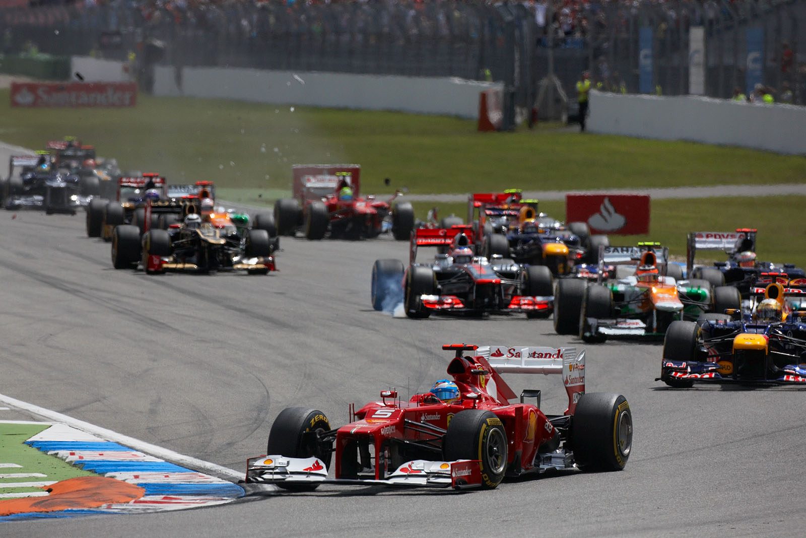 The start field approaches turn one, Ferrari's Alonso in the lead