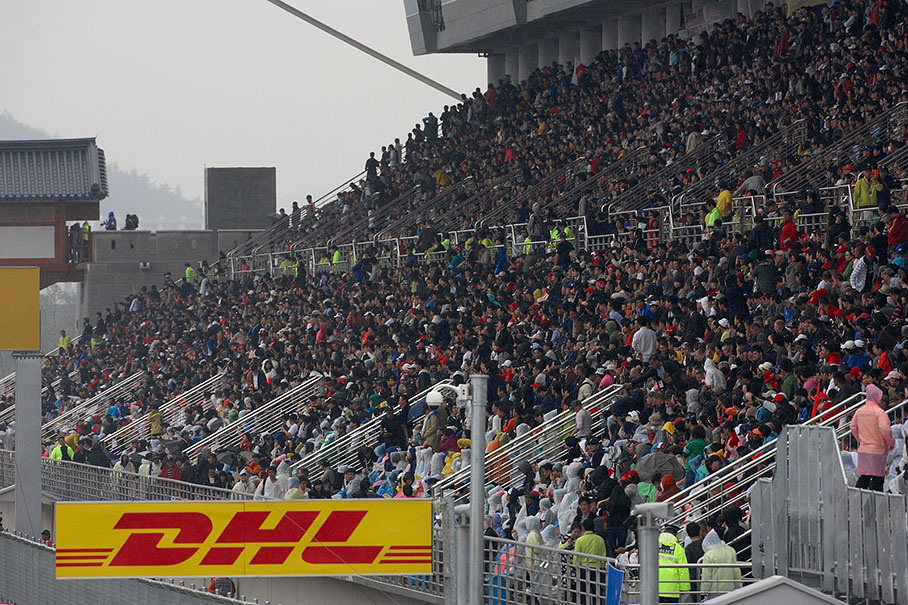 Korean race fans withstand the heavy rain on the roofed main grandstand