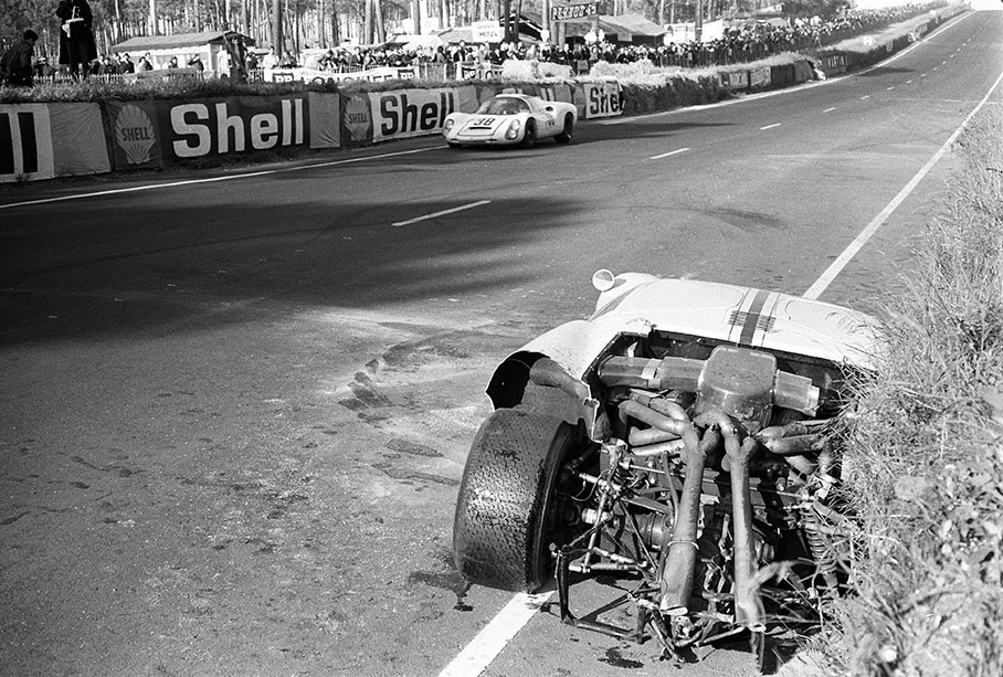 A damaged Ford GT40 besides the track, a lonely Porsche 910 #016 (S-ZL 693) passes by
