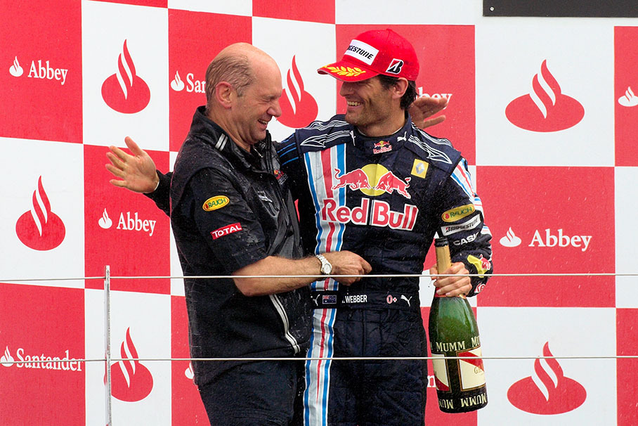 Champagne-soaked Red Bull driver Mark Webber and car designer Adrian Newey get on touch on the podium
