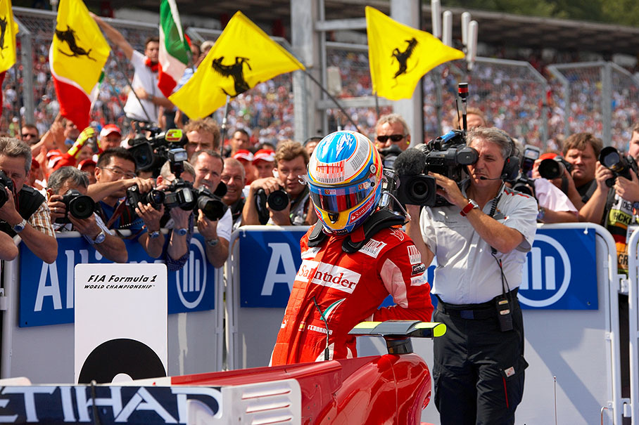 Race winner Alonso stretches his back in parc ferme