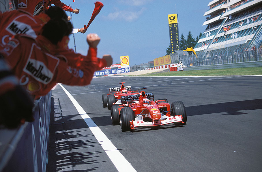 Rubens Barrichello and Michael Schumacher passing the cheering team