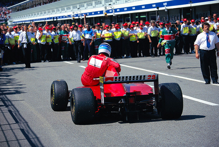 Mika Hakkinen, who retired with engine failure, is given a lift to park ferme by Gerhard Berger's Ferrari