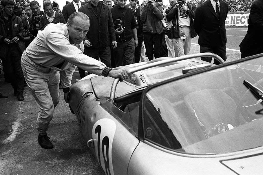 Followed by compassionate journalists, Edgar Barth (DDR) pushes his Porsche 718 WRS #047 without the right rear wheel through the pitlane towards his pit crew. He will finish the 24h race in 8th position, 39 laps behind the winner. 24h Le Mans 1963