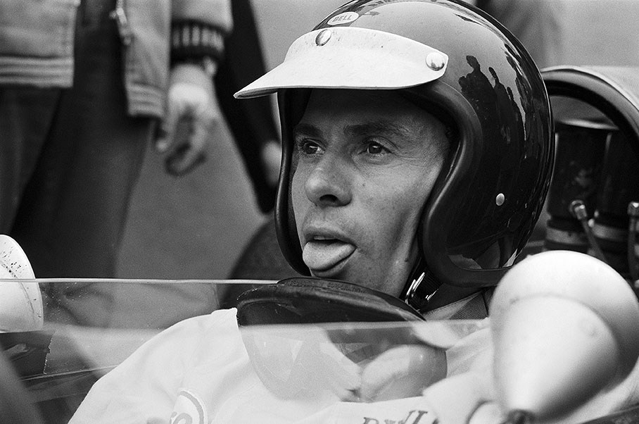 Jim Clark sticks his tongue out - perhaps as an amicable gesture to a companion besides the car?
