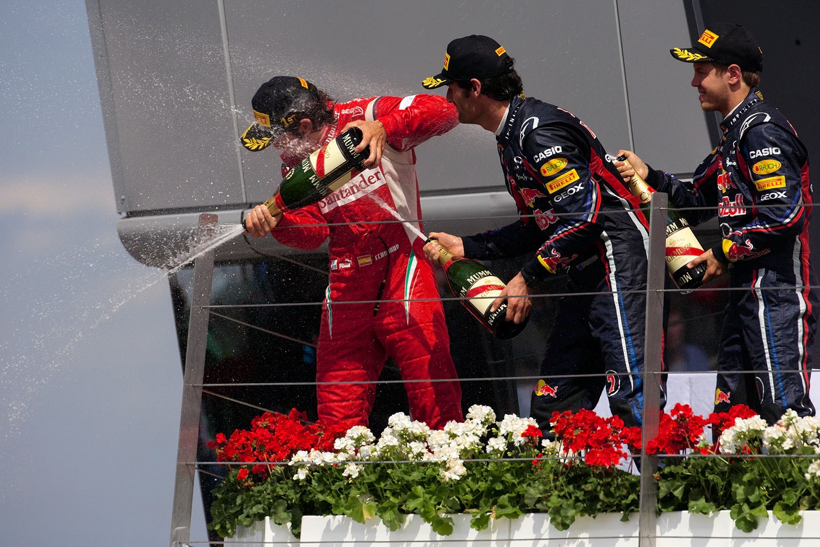 Alonso sprays champagne showers from the podium at the Ferrari team