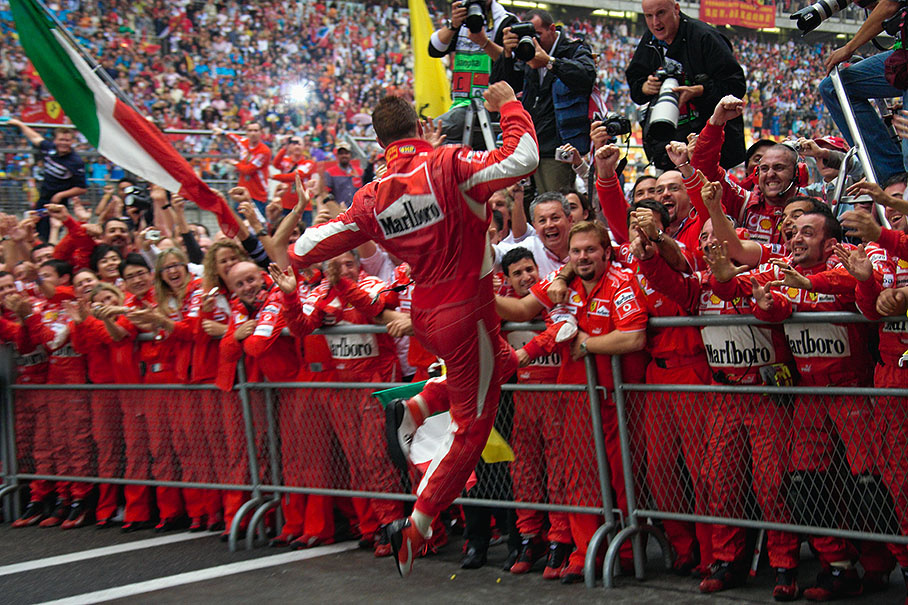Michael Schumacher jumps frenetically through parc ferme towards his waiting team