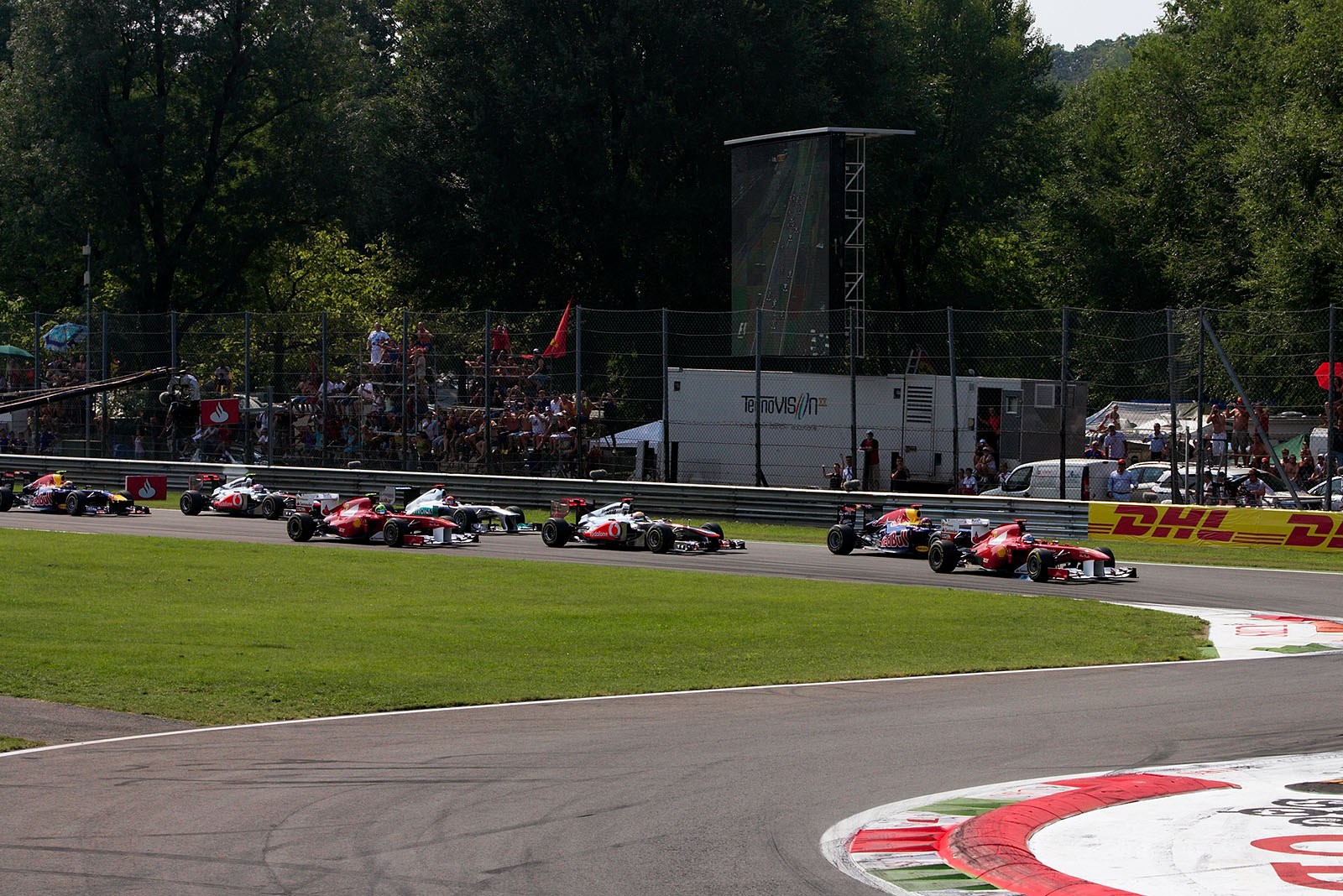 The start field approaches turn one, Alonso on Ferrari jumped to the front