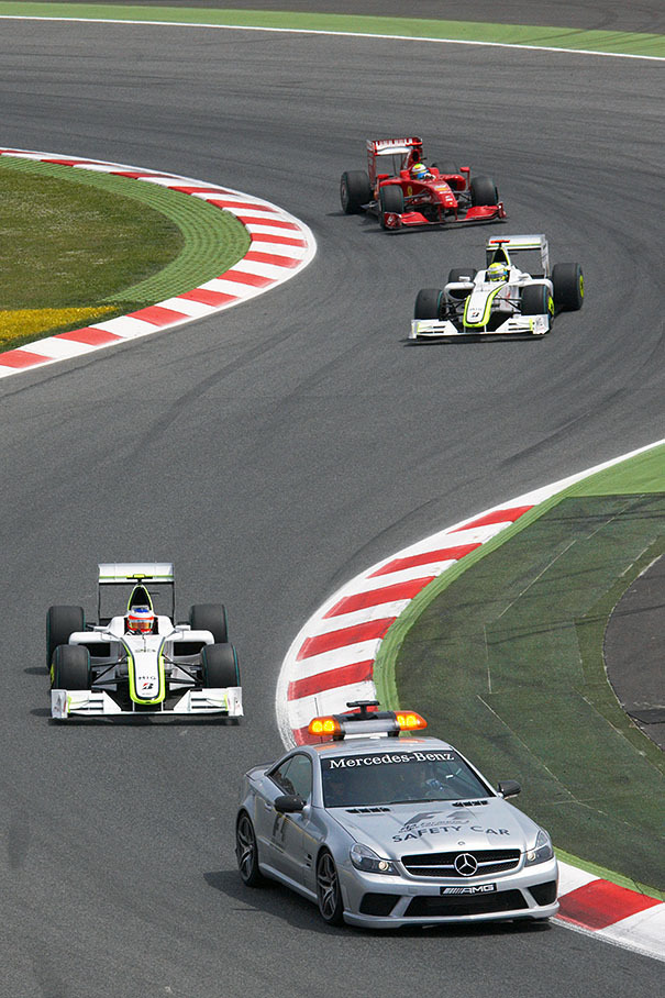 The safety car leads the Brawn GP cars and Massa's Ferrari after the start accident