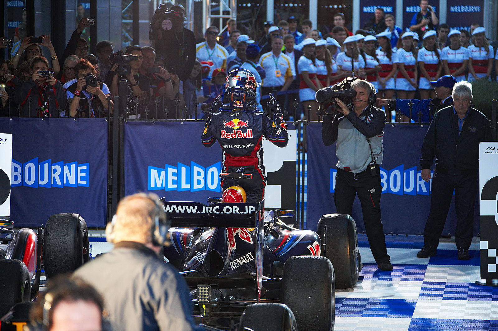 Sebastian Vettel stands in the Red Bull car in parc ferme and greets the fans on TV