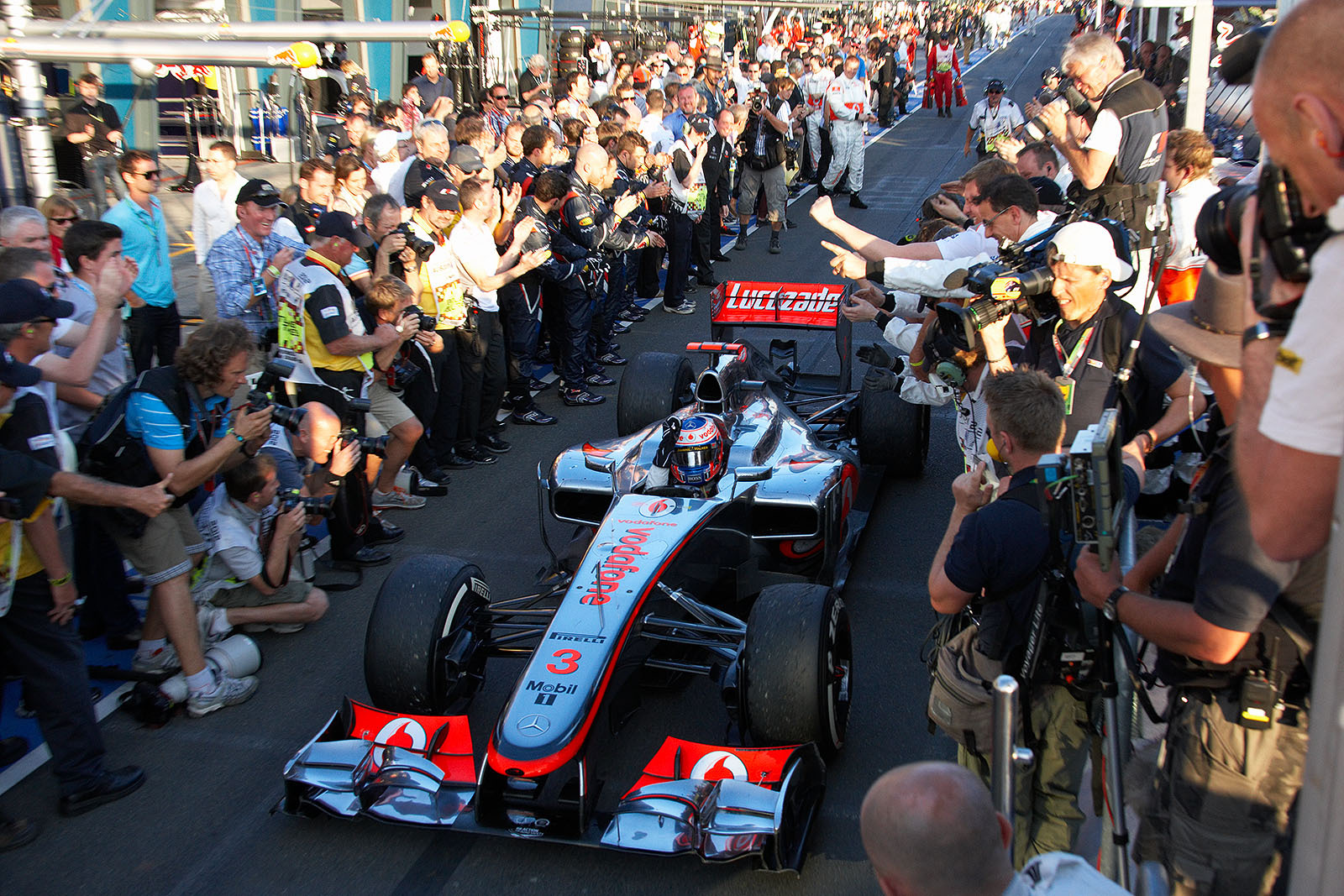 Race winner Jenson Button of McLaren arrives between the cheering folks after the first race in Melbourne 2012