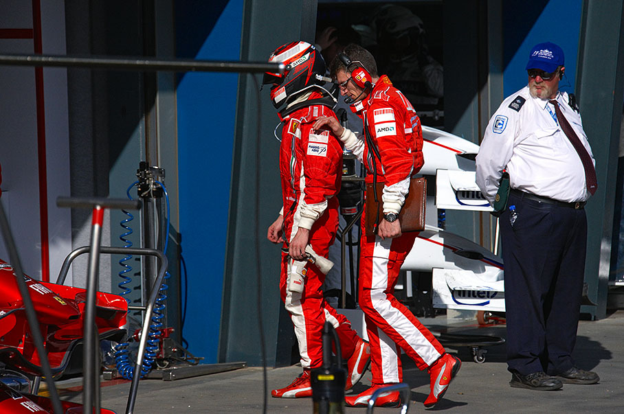 Under the eyes of alert officials and accompanied by soothing Ferrari engineer Chris Dyer, a seemingly disappointed Raikkonen walks back trough pitlane after retiring five laps before race end.