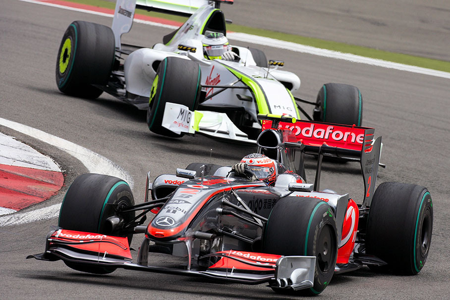 Kovalainen's McLaren Mercedes and Button's Brawn Mercedes dance around the curb at first turn
