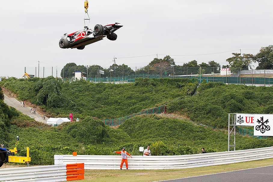 During Friday's practice session, the marshals lift Lewis Hamilton's McLaren Mercedes car besides the track