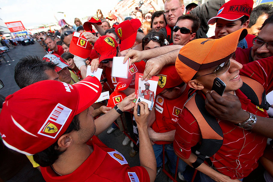 Ferrari fans wait in pit-line as the drivers sign autographs on thursday afternoon