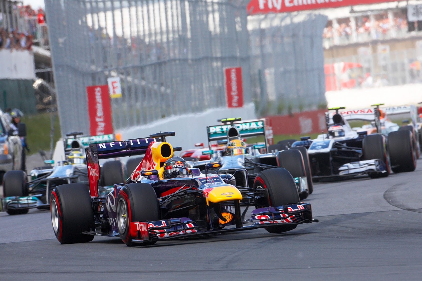 At the start, Sebastian Vettel of Red Bull Racing leads the field in front of Mercedes race drivers Hamilton and Rosberg
