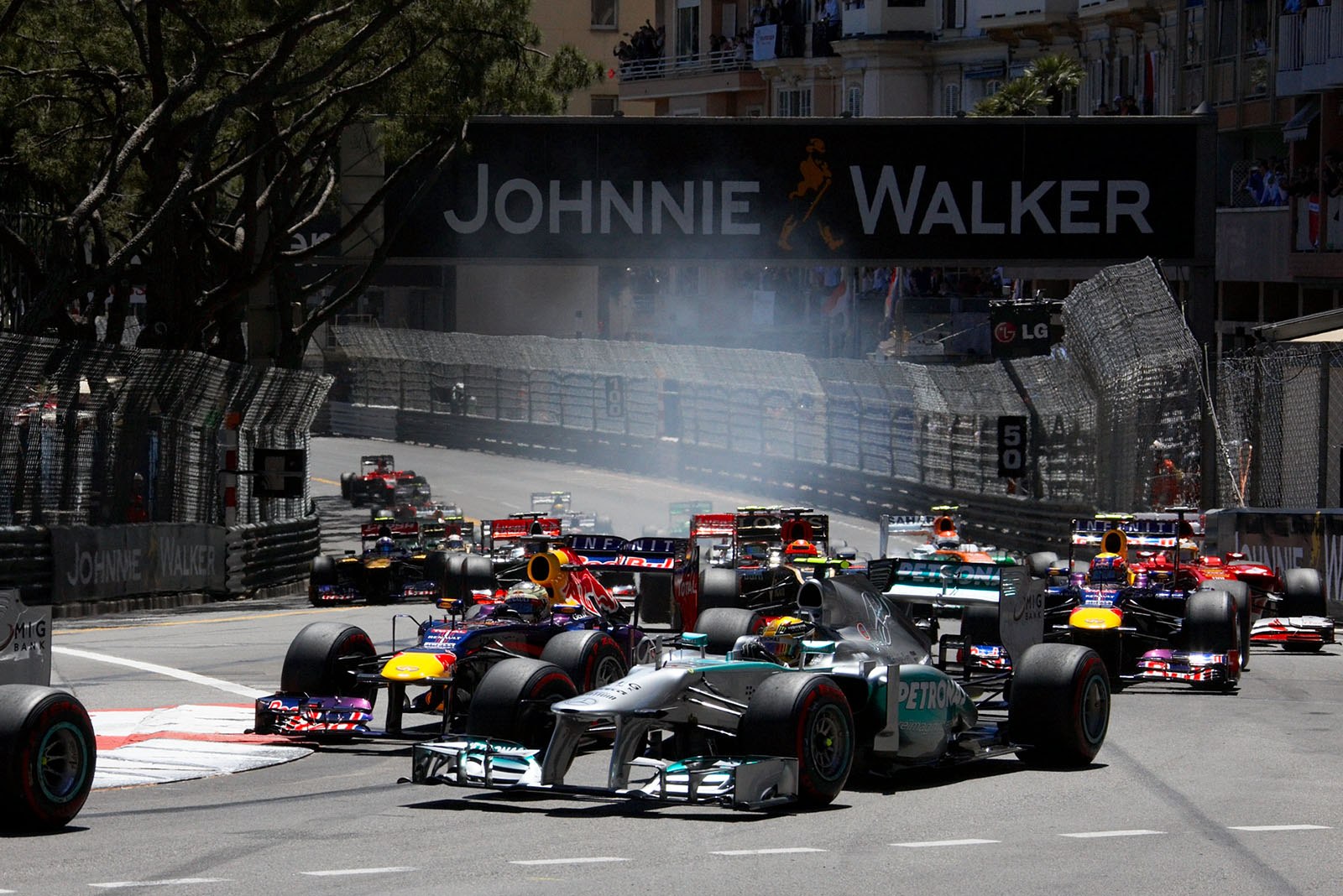 The start field approaches turn one, Lewis Hamilton of Mercedes slightly in front of opponent Vettel