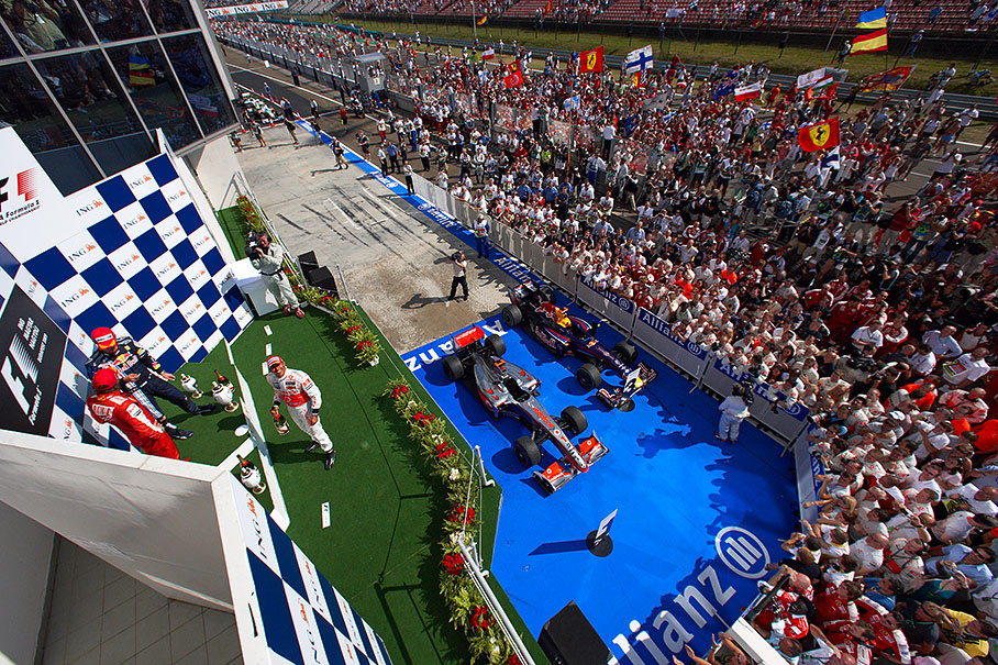 Race winner Lewis Hamilton grins into the lens in front of second placed Kimi Raikkonen and third placed Mark Webber