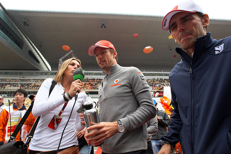 Jenson Button is being interviewed on his way back from driver parade, being passed by Pedro de la Rosa