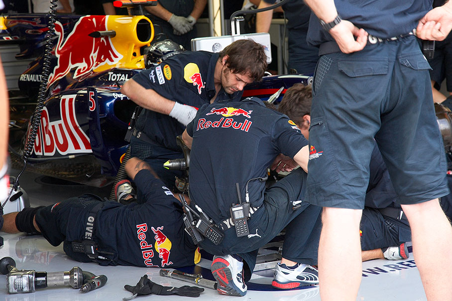 Mechanics work at a Red Bull Racing car's front suspension