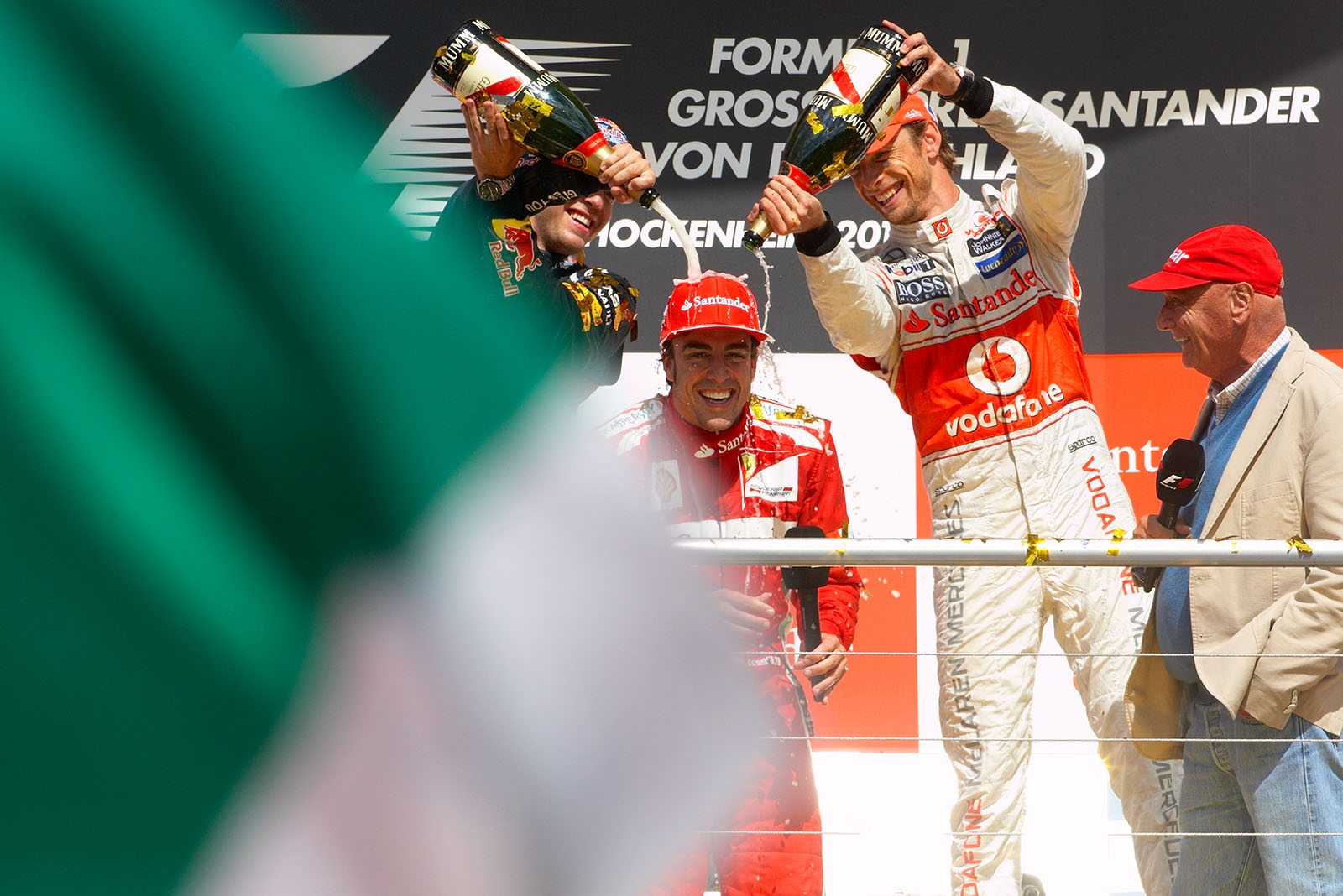 Race winner Fernando Alonsoenjoys a champagne shower of Sebastian Vettel and Jenson Button on the podium after the German Grand Prix