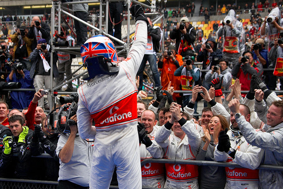Race winner Jenson Button celebrates with his McLaren team members and his fiance Michibata at parc ferme fence