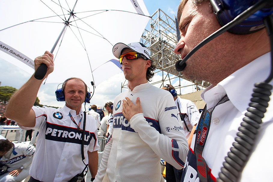 Physio Jo Leberer holds the umbrella for Kubica