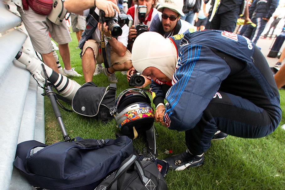 Surrounded by photographers, Sebastian Vettel shortens his drink hose besides the grid