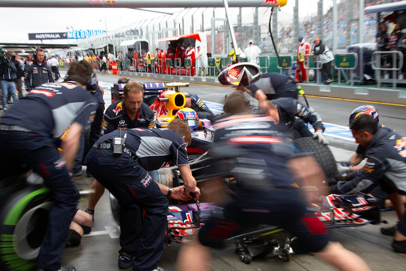 Mark Webber practises stops with the Red Bull Racing pit crew