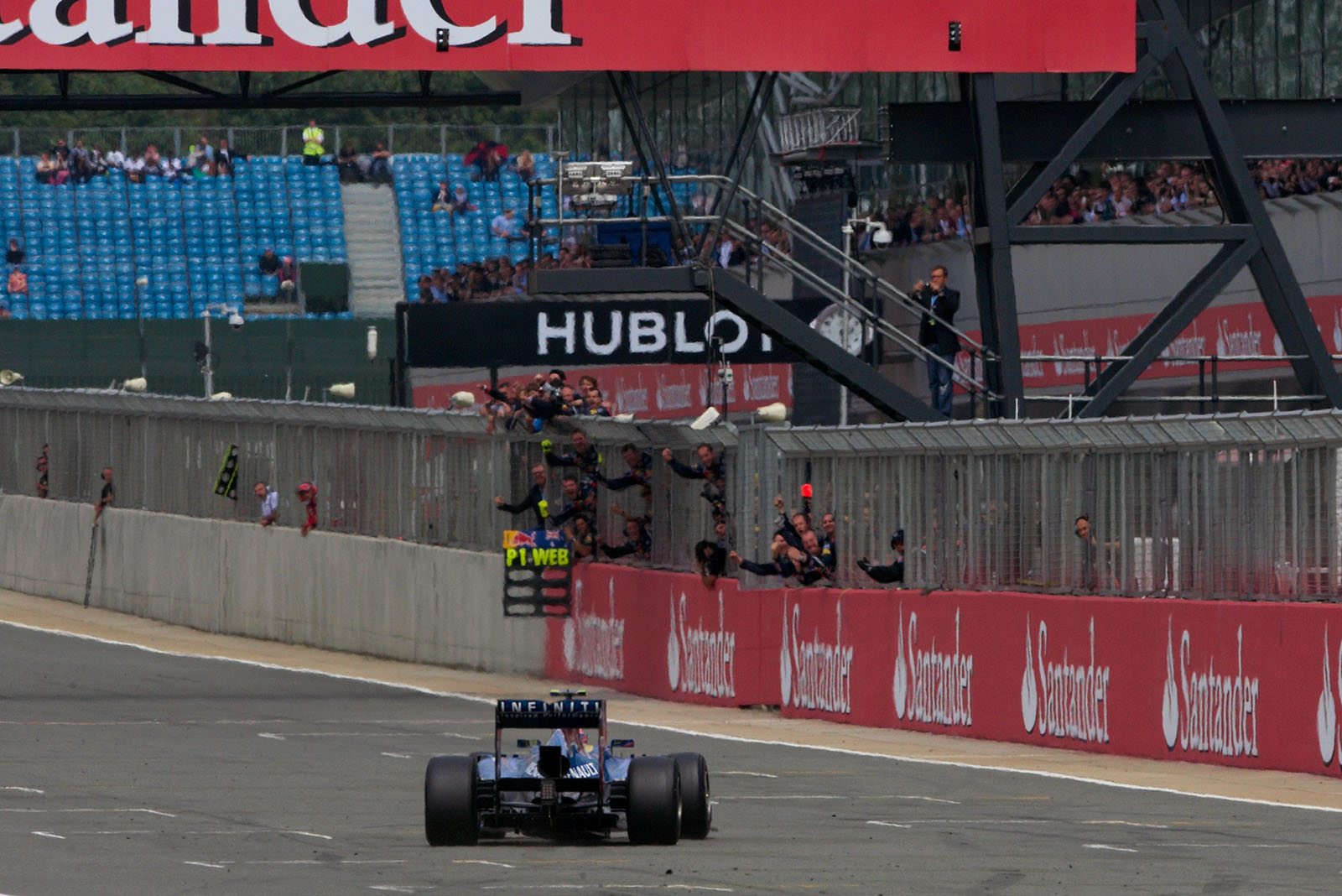 Race winner Mark Webber of Red Bull Racing passes his cheering team after taking the chequered flag